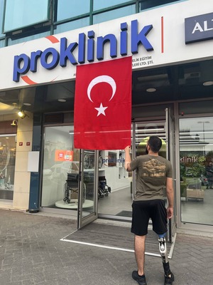 kol protezi bacak protezi takılan memnun kullanıcı türk bayrağını tutuyor