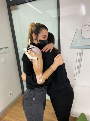 biyonik protez kol takılan genç kadın proklinik çalışanına sarılıyor